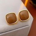 Primer plano de pendientes vintage franceses de cuero marrón con montura de metal dorado - café
