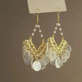 Detail of gold hollow bow earrings featuring dangling shell pieces and elegant pearls - Earring Hooks / White