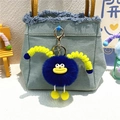 Detail of cute blue plush monster keychain with yellow lips hanging on a denim bag - Royal Blue