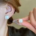 Macro shot of square pearl stud earrings with iridescent luster on female model ear - 12mm / 12mm White