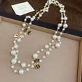 Detailed view of French enamel bow accents on a layered white pearl necklace - Necklace-White-Black
