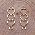 Vista macro di connettori a cuore traforati in oro rosa per gioielli DIY su legno - Oro KC