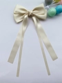 Vue détaillée du nœud en satin crème avec de longs rubans en soie et une finition brillante - Beige