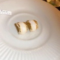 Close-up of gold-plated C-shaped hoop earrings with iridescent pearl inlays on a ceramic plate - Beige C-Shape