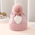 Detail of pink knitted baby hat with white heart pattern and fluffy pompom - One Size 0-12 Months / Pink