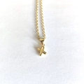 Close-up of a minimalist gold letter X pendant necklace on a clean white background - Letter X