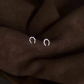 Primer plano macro de pendientes de plata en forma de U con circonitas brillantes - Oro Blanco