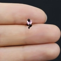 Macro di un piccolo orecchino a serpente nero con zircone a cuore rosa tra le dita - Serpente Nero Cuore Rosa