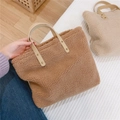 Close-up of caramel fleece handbag with leather handles and metal rivet details - Camel