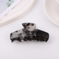 Dettaglio di un grande fermaglio per capelli in acetato con eleganti motivi in marmo nero - Nero