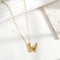 Chubby golden alphabet W pendant necklace on minimalist stone background - Letter W