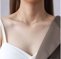 Primo piano di una delicata collana a catena d'argento con un piccolo ciondolo di perla bianca - Stile A Perla Singola / Argento