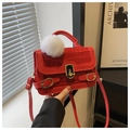 Detail einer roten Handtasche mit Krokoprägung, Plüschanhänger und goldenem Verschluss - Rot