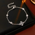 Detalle de pulsera ajustable de flor plateada con circones sobre cuero negro - Plateado