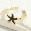 Goldener verstellbarer Ring mit schwarzem Emaille-Seestern und goldener Perlenverzierung - Schwarze Seestern (JZ0254)
