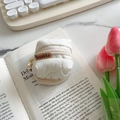 Custodia AirPods trapuntata bianca con cerniera e ciondolo a perla su sfondo di libri - Bianco Latte