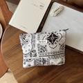Detail van linnen paisley make-uptasje met 'simple wish' label op een houten bureau - Groot Geometrisch Raster