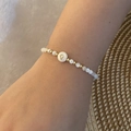 Detail van de parelarmband met letter Q, witte parels en gouden accenten op de pols - Letter Q Stijl (Q)