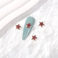 Pink star-shaped alloy nail charms with crystals set on a light blue nail tip - Gold Rose Red Zirconia
