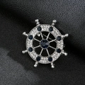 Macro shot of silver nautical helm brooch with blue crystals and sparkling rhinestones - Rudder Silver Blue Stone