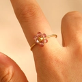 Detaillierte Nahaufnahme eines handgefertigten Golddrahtrings mit rosa Kristallblume - Lila