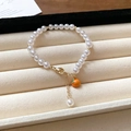 Gold plated pearl bracelet featuring a cute orange enamel charm and lobster clasp - Orange