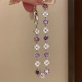 Detailansicht eines silbernen Blumenarmbands mit lila Steinen und Kleeblatt-Akzenten - Lila Blume