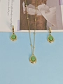 Golden necklace and earring set featuring oval green gemstone pendants on art magazine - Imperial Green