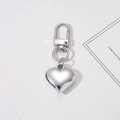 Close-up of heart-shaped silver metal keychain with D-ring clasp on white card - Heart