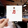 Detail of red enamel musical note brooch with gold trim on white display card - 142*Red Musical Notes Pin