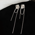 Detalle de pendientes de flor plateada con borlas largas de cadena sobre fondo negro texturizado - Plateado (Silver Earring Post)