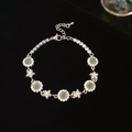 Dettaglio del bracciale a fiori con pietre verdi e ciondoli a stella su velluto nero - Stile Fiore Stella Argento Verde