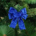 Blue glitter Christmas bow ornament on tree branch for festive holiday decoration - Blue