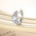Single silver huggie earring with clear zircon stones on a beige background - White