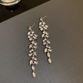 Detalle de pendientes de borla plateados con circonitas en diseño de hojas - Estilo de Borla de Hoja Plateada