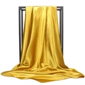 Detailed view of golden satin fabric hanging on a rack showing smooth silk texture - Ginger Yellow