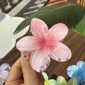 Pink plumeria hair claw clip with jelly texture held against a wooden background - Plumeria Jelly Texture / Peach Blossom Pink
