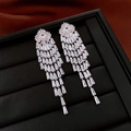 Macro shot of silver tassel earrings with sparkling zircons on a black jewelry display - Silver
