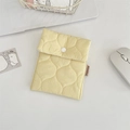 Close-up of a yellow quilted mini storage pouch with wave stitching and a white button - Bright yellow