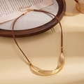 Close-up of the elegant matte gold twisted pendant and minimalist brown rope chain detail - Gold