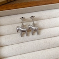 Dettaglio di orecchini a cavallo in argento con pietre nere in una scatola per gioielli - Orecchino a Bottone con Ciondolo a Cavallo a Forma di C in Zirconia e Metallo con Perno in Argento