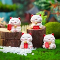 Set of four white resin lucky cat figurines with red scrolls on a natural mossy base - Lucky Cat Blessing Set