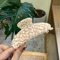 Detail of star pattern acetate hair claw clip held in hand with marble texture finish - Large / Clear Orange Star