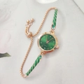 Detail of green quartz watch and gold adjustable bracelet set on white marble background - Green