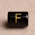 Macro shot of a black cylindrical bead featuring a gold-stamped letter F for DIY jewelry - Letter F