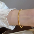 Collana dorata scintillante effetto cielo stellato indossata al polso con maglia bianca - Bracciale / Bracciale Oro