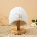 Dettaglio del berretto bianco a coste con lettera R ricamata in beige sul risvolto - M / Bianco