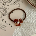 Detail of amber tortoiseshell floral hair tie with a white pearl on a beige card - Marble Brown
