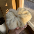 Coletero de piel sintética beige sostenido por una mano, textura suave y estilo de invierno - Blanco Roto
