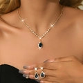 Detailed close-up of zircon necklace and drop earrings set with blue pear-shaped stones - 2-Piece Set / Gold Dark Blue Gem